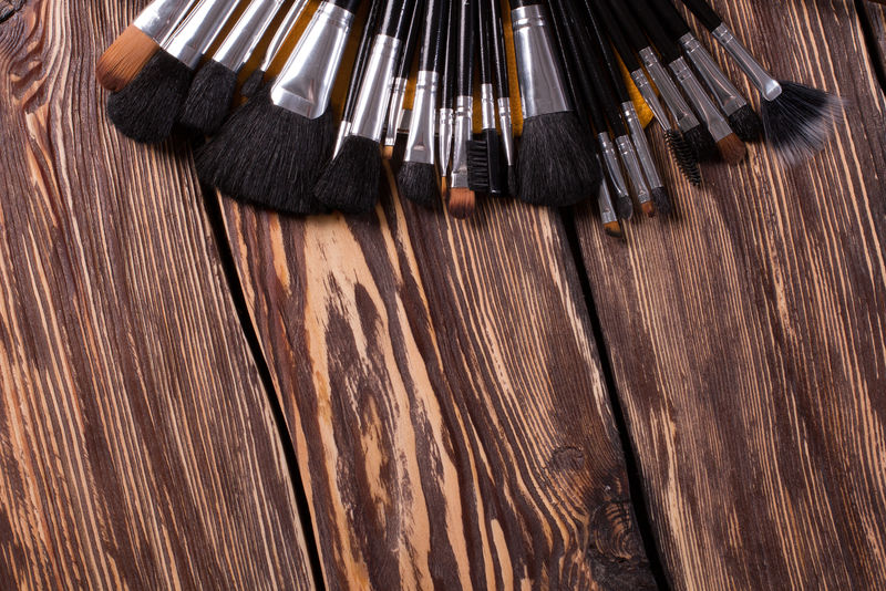 一套不同的刷子用于在木质背景上化妆专业化妆配件