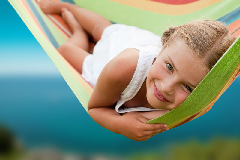 暑假-可爱的女孩在彩色吊床上休息