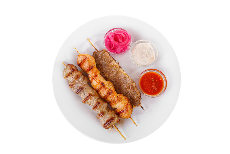 烤肉串牛肉羊肉猪肉烤肉架上的鸡肉烧烤没有装饰的盘子上孤立的白色背景腌洋葱蛋黄酱焦油番茄酱番茄酱从上面看