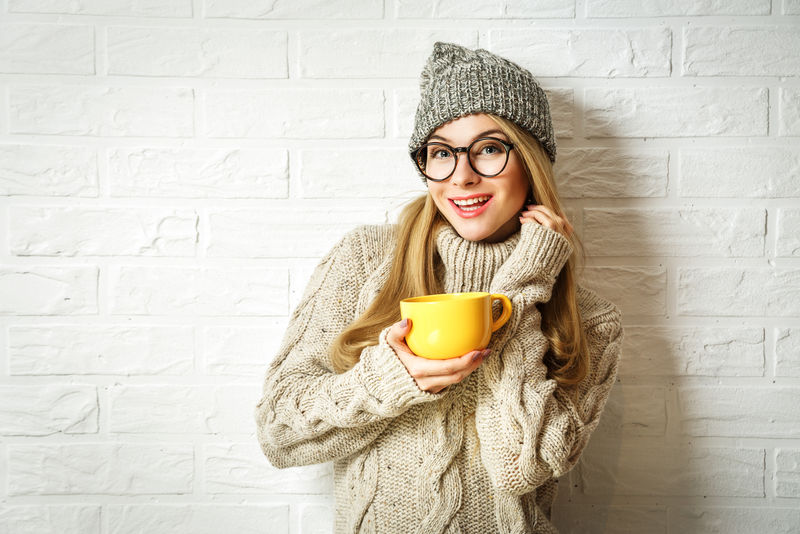 穿着冬装带着杯子的漂亮害羞的时髦女孩