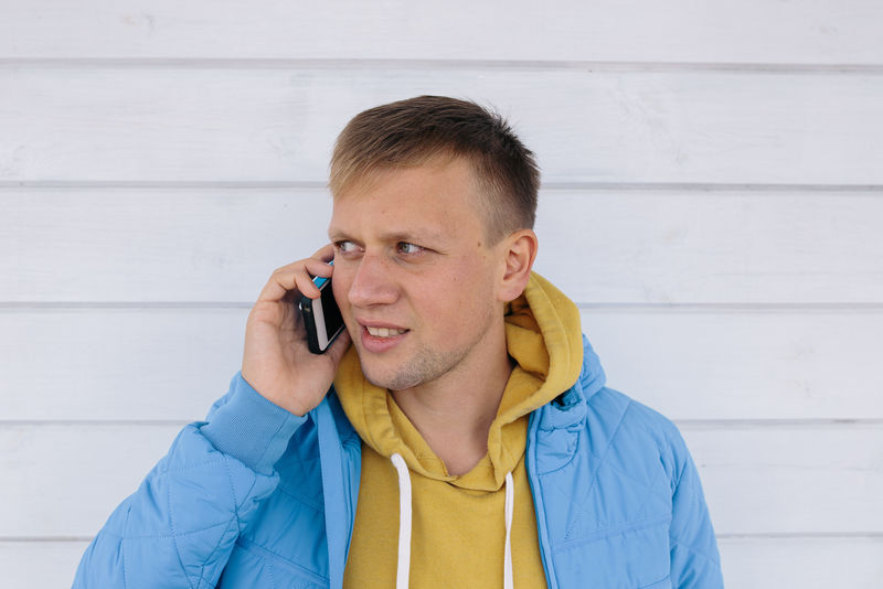 年轻人在打电话在白木背景下使用智能手机的人