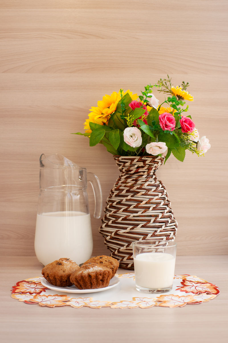 早餐从牛奶和蛋糕在绣花餐巾花编织花瓶创造舒适