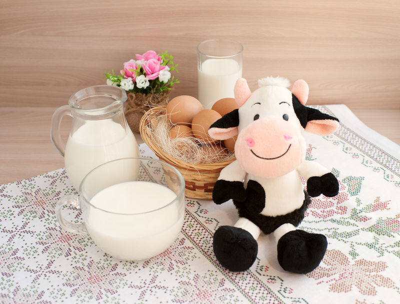 牛奶在玻璃器皿和鸡蛋做早餐有趣的玩具牛象征着乳制品