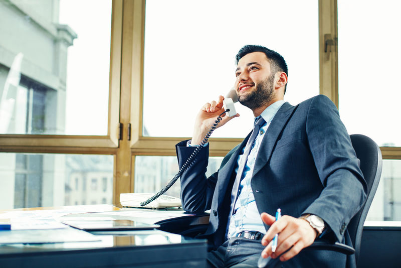 在办公室打电话的年轻商人