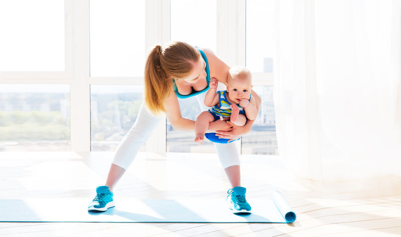 运动妈妈在家里和宝宝一起做健身和瑜伽