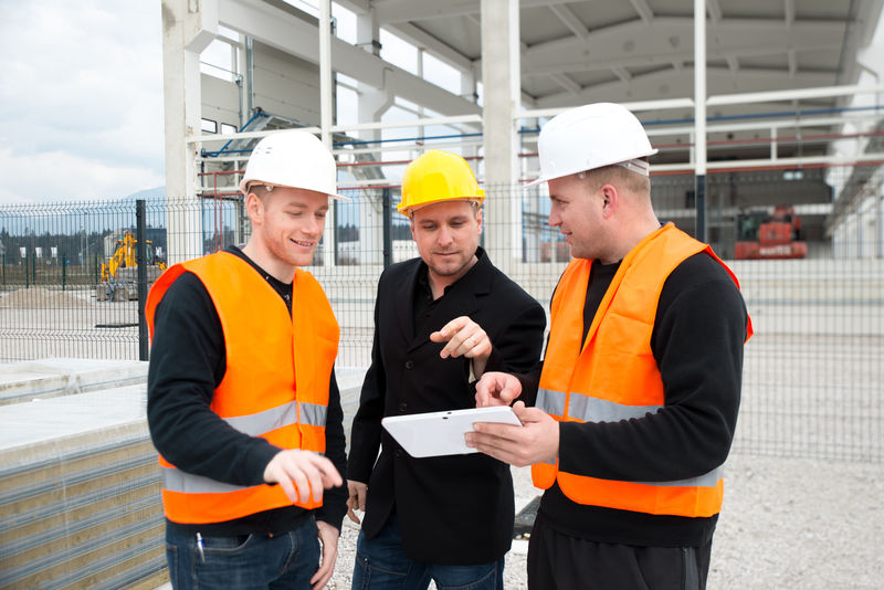 两名建筑工人和建筑师检查建筑物的地图