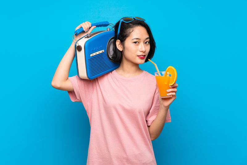 亚洲年轻女子手持收音机背景为蓝色