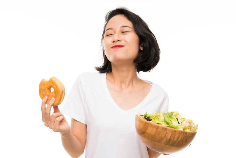 独立背景的亚洲年轻女子配沙拉和甜甜圈