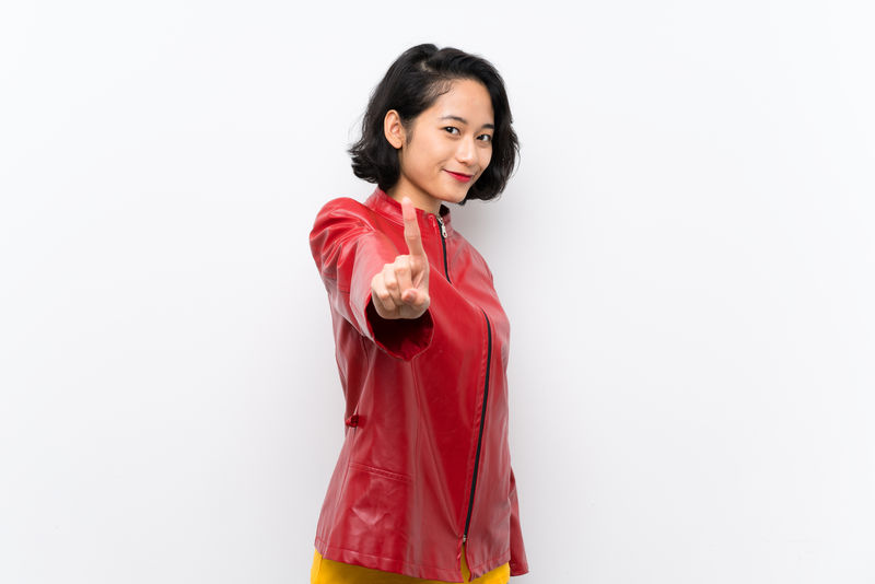 亚洲年轻女子在孤立的白色背景下展示和举起手指