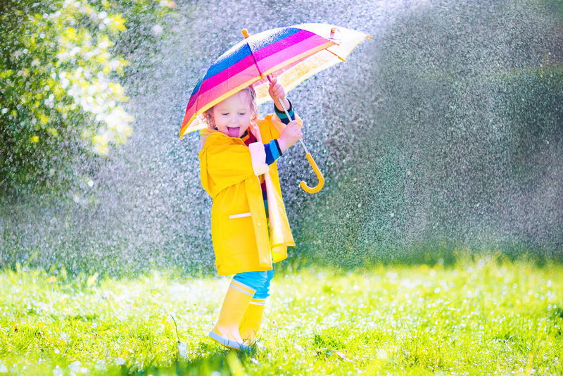 在雨中玩伞的有趣的幼儿漂亮孩子