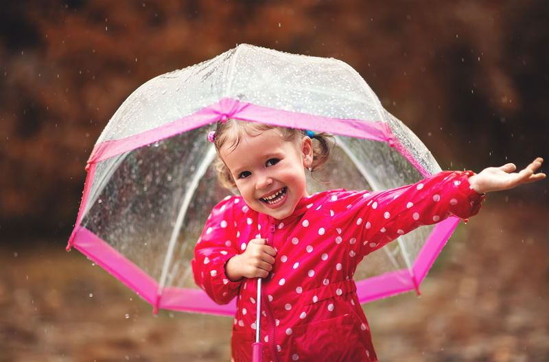 快乐的小女孩在雨中拿着雨伞大笑可爱的人