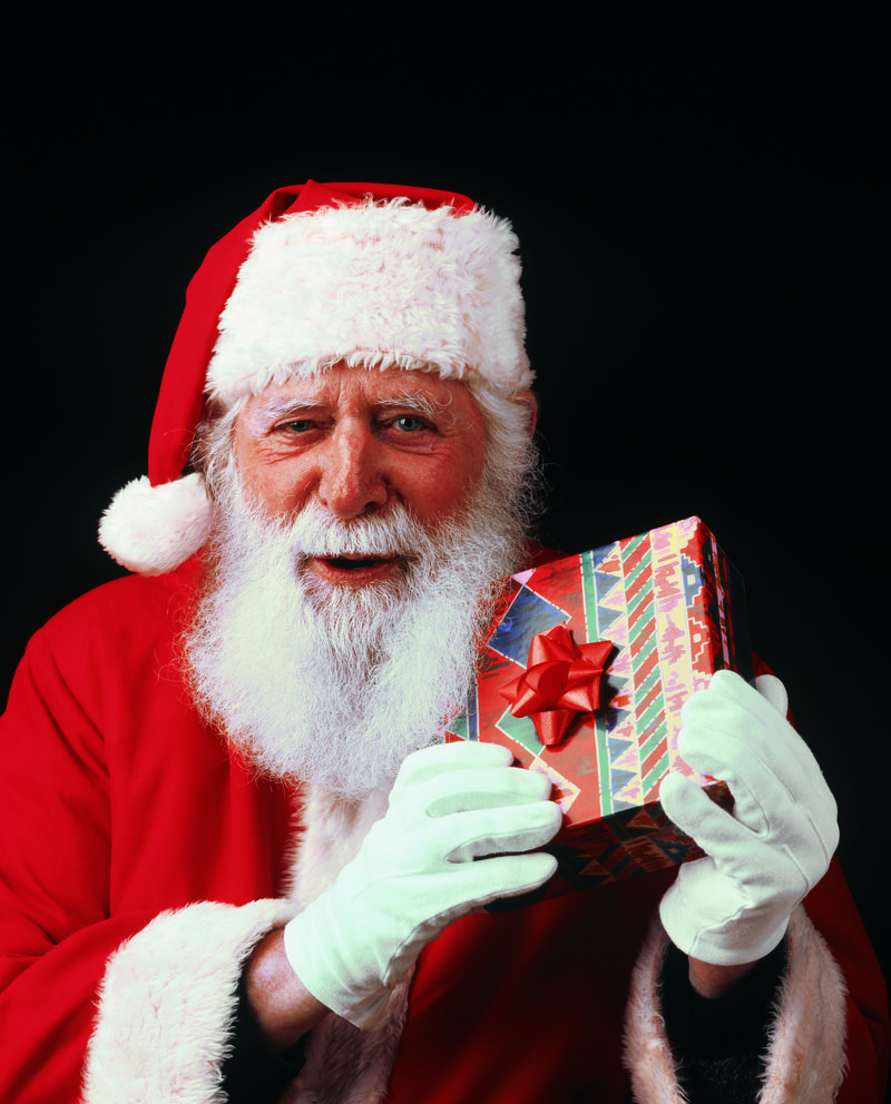 快乐圣诞老人带着礼品盒看相机
