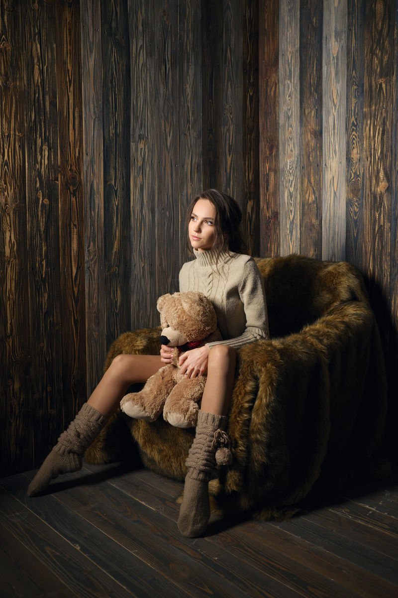 可爱的女孩穿着暖膝袜子和毛衣中间夹着泰迪熊