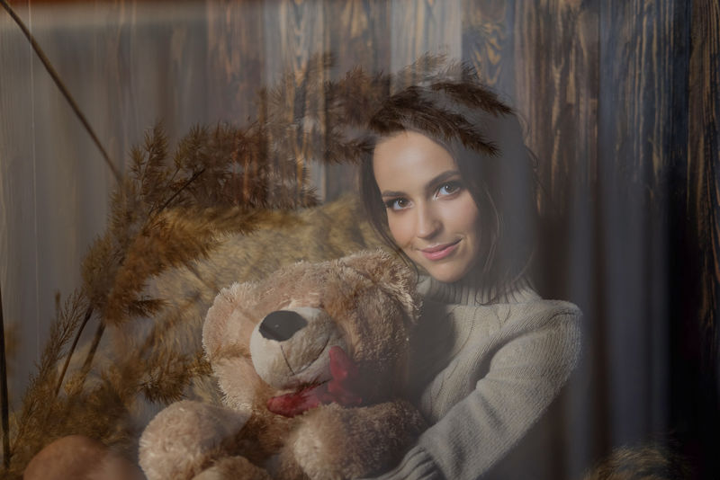 穿着暖膝袜子和毛衣的可爱女孩穿着泰迪熊