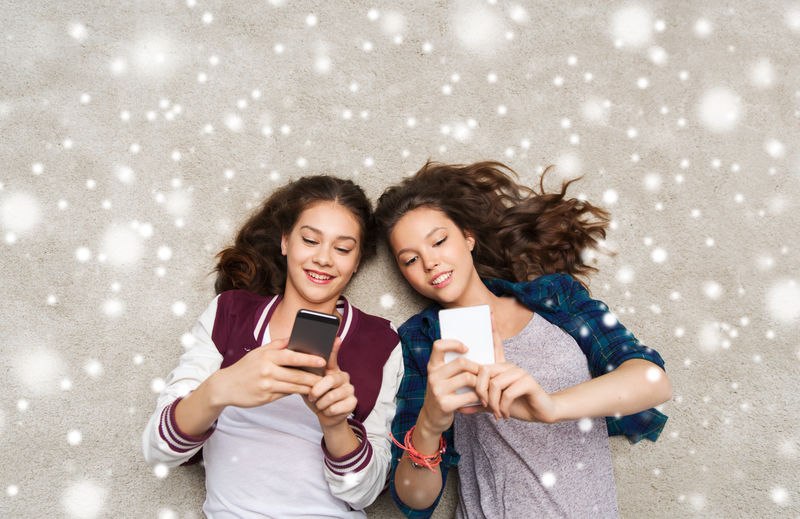 带着智能手机躺在地板上的快乐少女