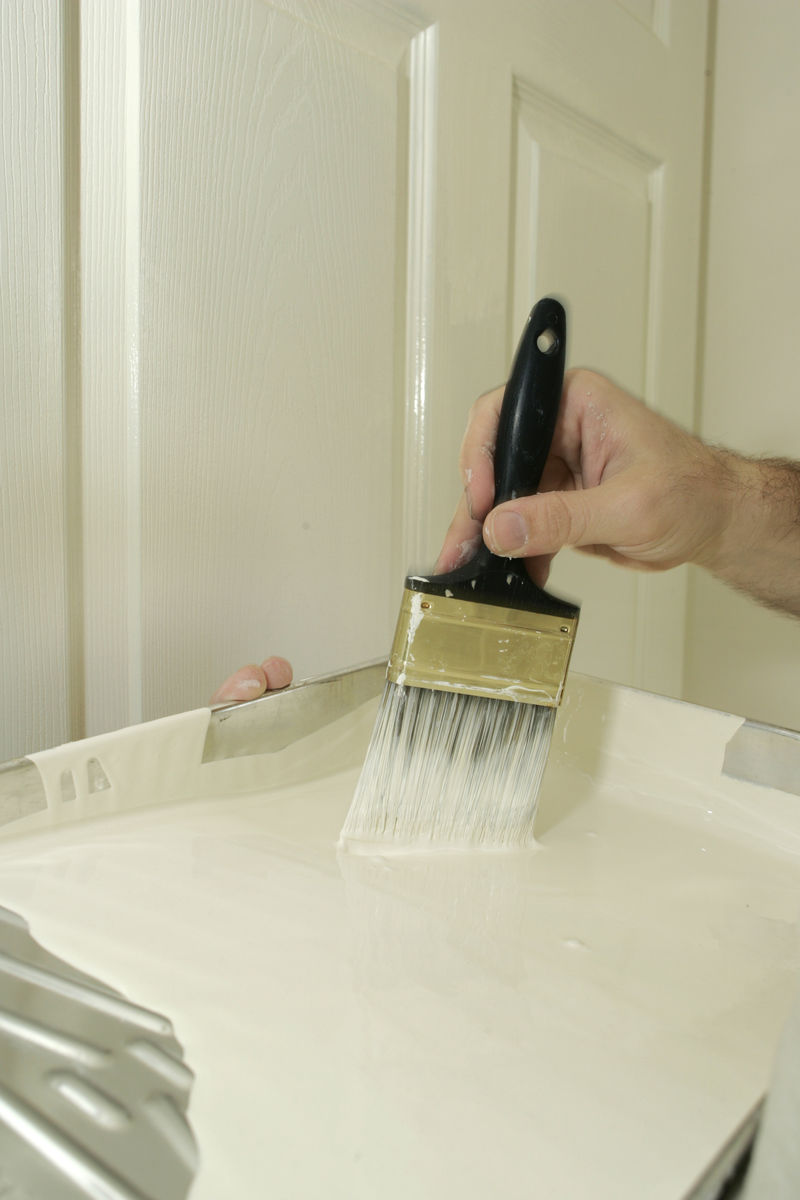 油漆工将刷子蘸上白色油漆