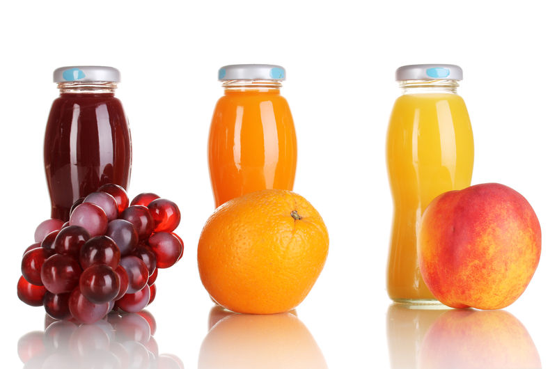 美味的葡萄橘子和苹果汁装在玻璃瓶内旁边的水果白色隔离