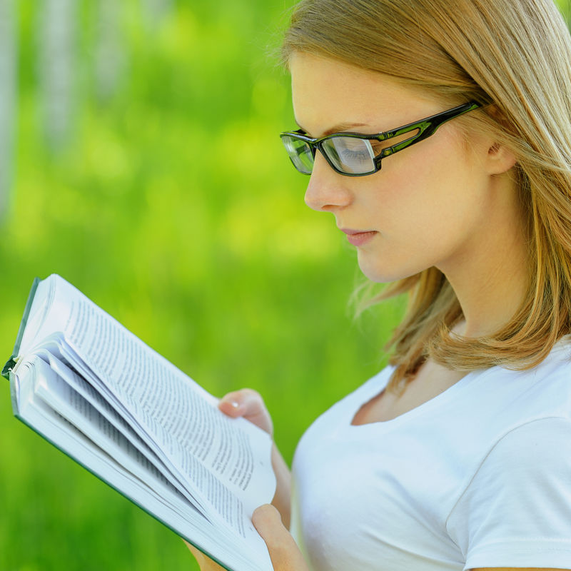 一幅年轻迷人的金发女人拿着书 穿着白衣服 戴着眼镜 站在夏绿园的画像素材 高清图片 摄影照片 寻图免费打包下载