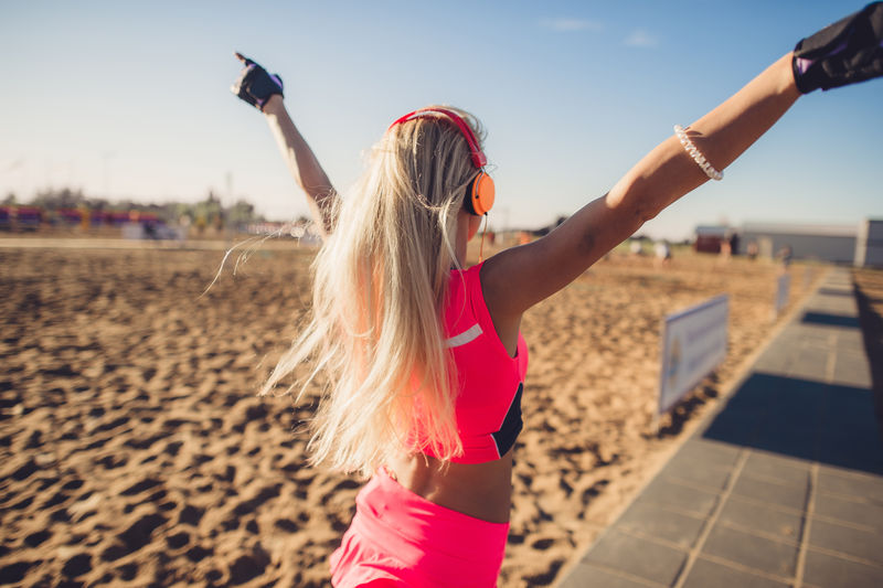 成功健身女性概念与运动臂章和耳机获胜的概念是女性运动员用双臂欢呼以达到减肥或人生目标