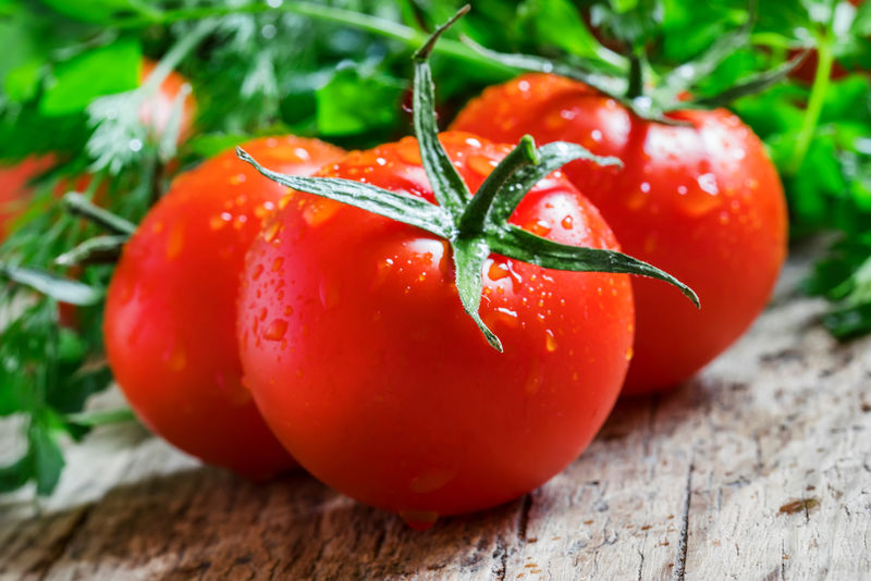 成熟的红色番茄在旧木背景上滴上水滴