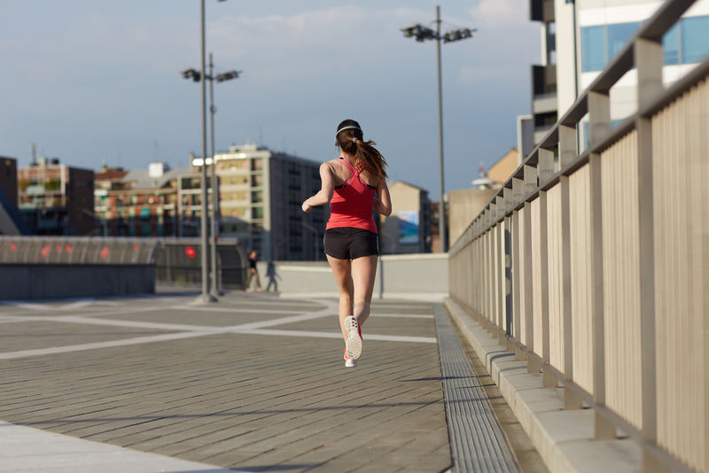 年轻漂亮的女子在城市街道上听音乐