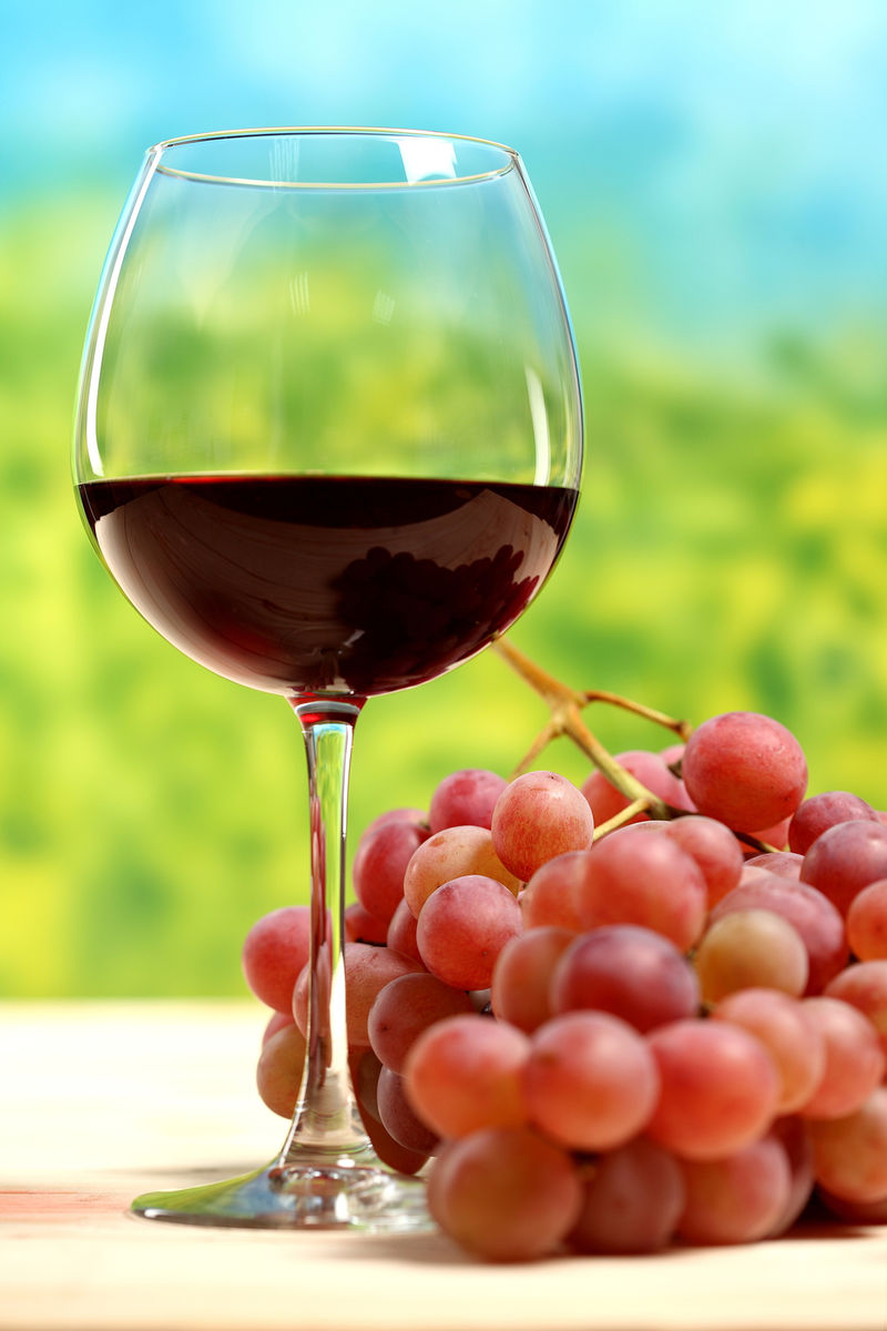 木桌上放着葡萄和树叶的一杯葡萄酒