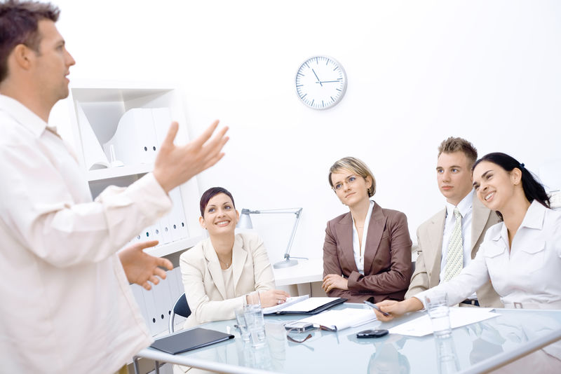 商人站着向坐在前面的四位同事解释