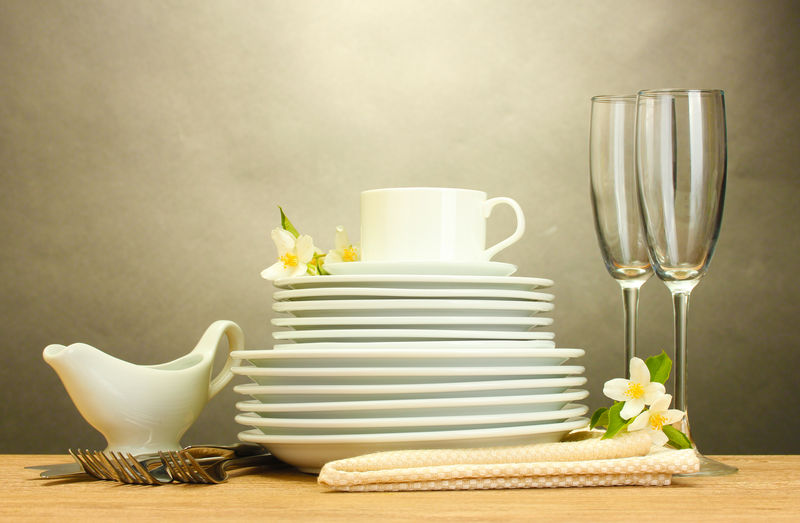 将干净的盘子玻璃杯和杯子倒在灰色背景的木桌上