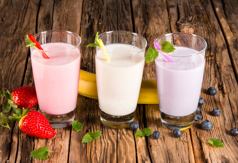 新鲜牛奶草莓蓝莓和香蕉饮料放在木桌上-配以新鲜水果的各种蛋白质鸡尾酒