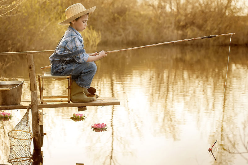 小男孩日落时在湖边钓鱼