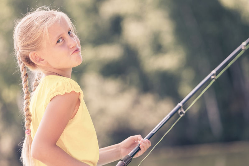 坐在岸边钓鱼的可爱女孩的肖像
