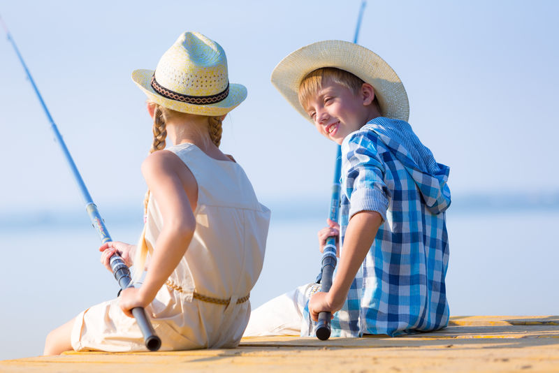 男孩和女孩用鱼竿从码头一起钓鱼