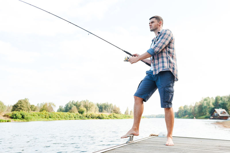 好好钓鱼-站在码头边垂钓的自信十足的年轻人