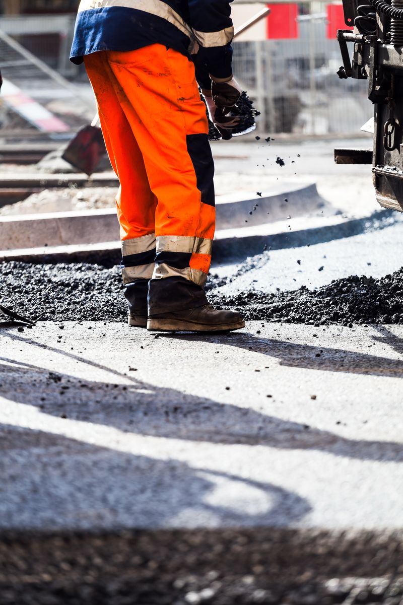 道路施工工业和团队合作的工人-在新柏油路上工作的人