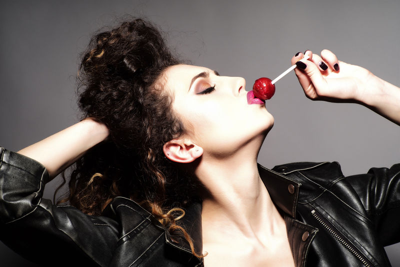 时髦的女人-卷发-穿着皮夹克-吃棒棒糖