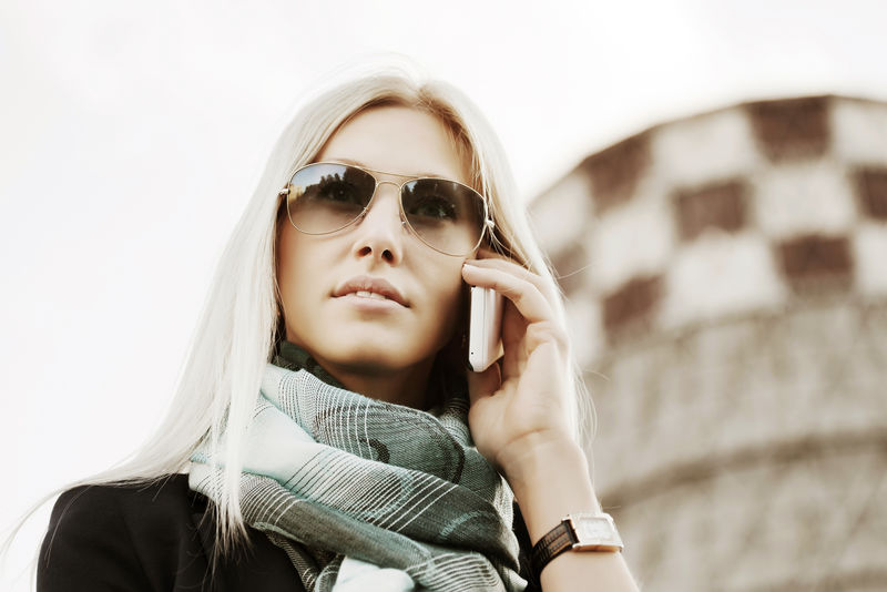 户外打手机的金发时尚商务女性