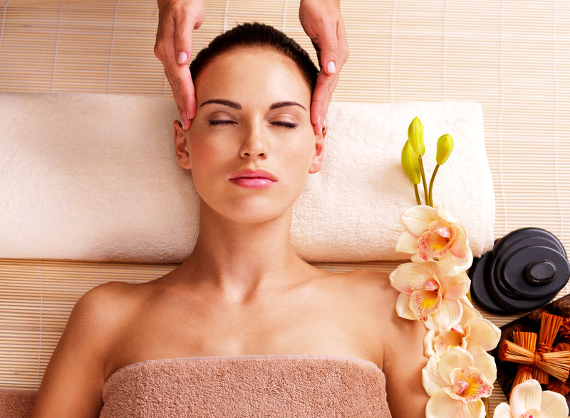 按摩师在水疗沙龙给一位成年妇女按摩头