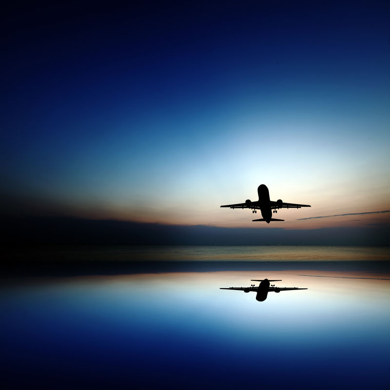 一架飞机的轮廓带着反射进入一个超现实色彩的夜空