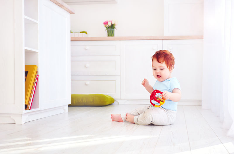 可爱的姜黄色小男孩在明亮的厨房玩玩具,在家里。