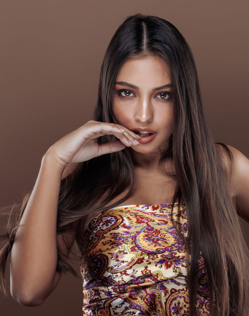 可爱的快乐印度年轻女人在工作室闭幕微笑，