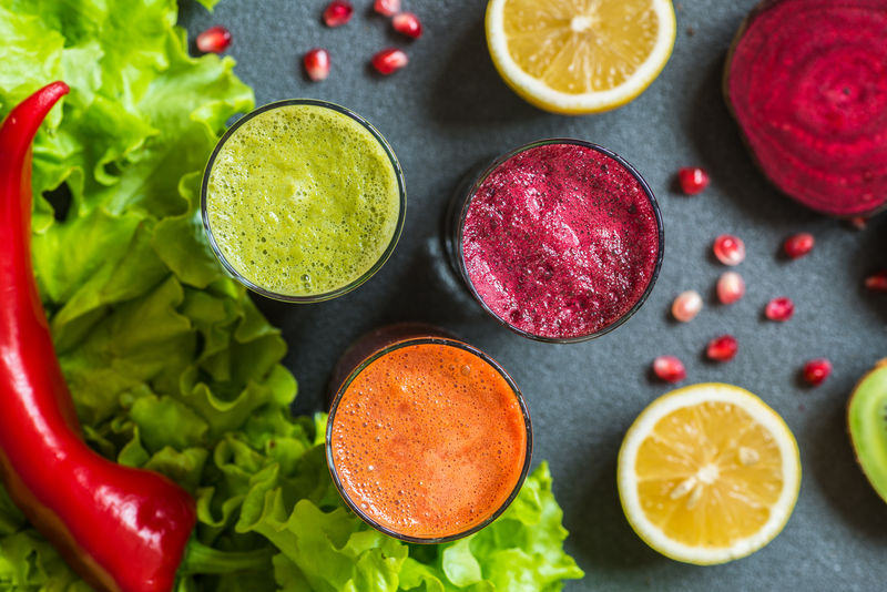 三杯不同的新鲜果汁。灰色背景下甜菜、胡萝卜和猕猴桃汁