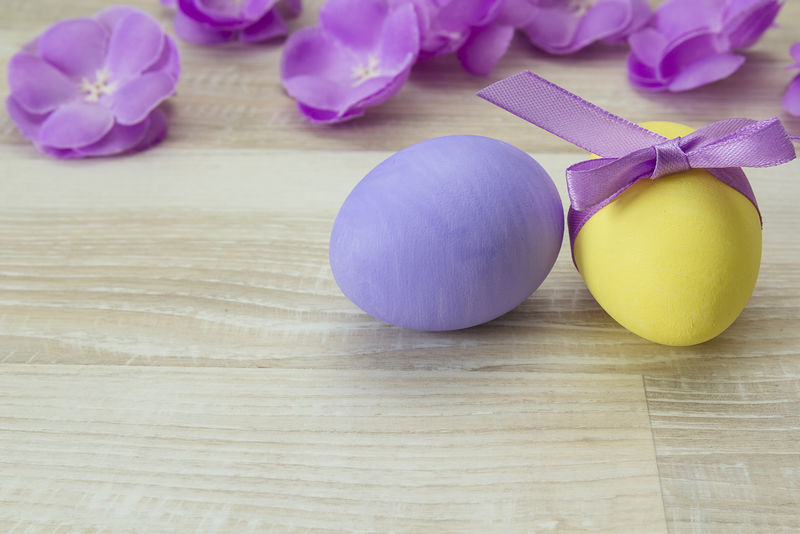 复活节彩蛋和紫色花在木制背景上。