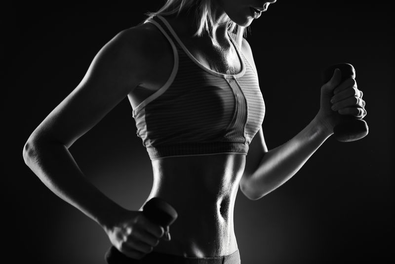 在运动服的哑铃锻炼苗条的女性身体