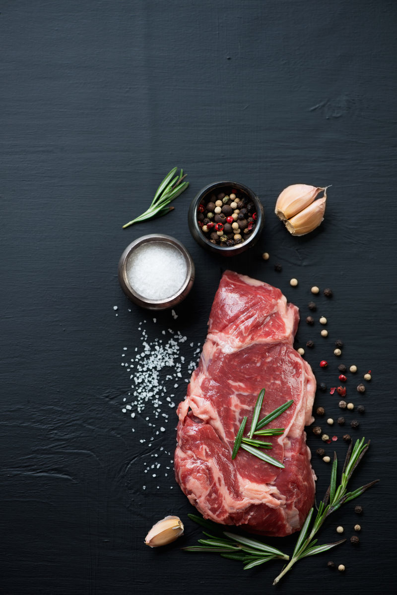 原味里贝耶牛排配调味料，黑色木质背景