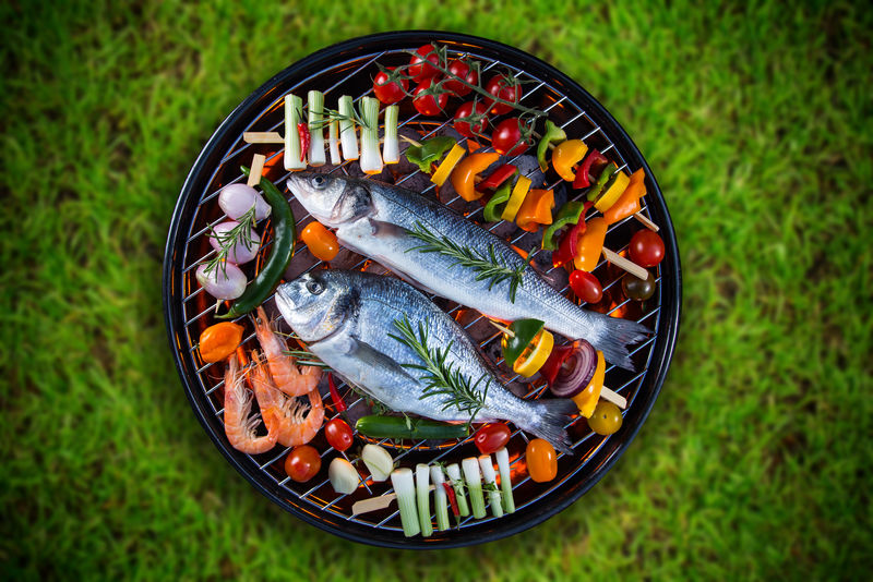 烧烤架上有蔬菜、串肉和对虾的烤海鱼。
