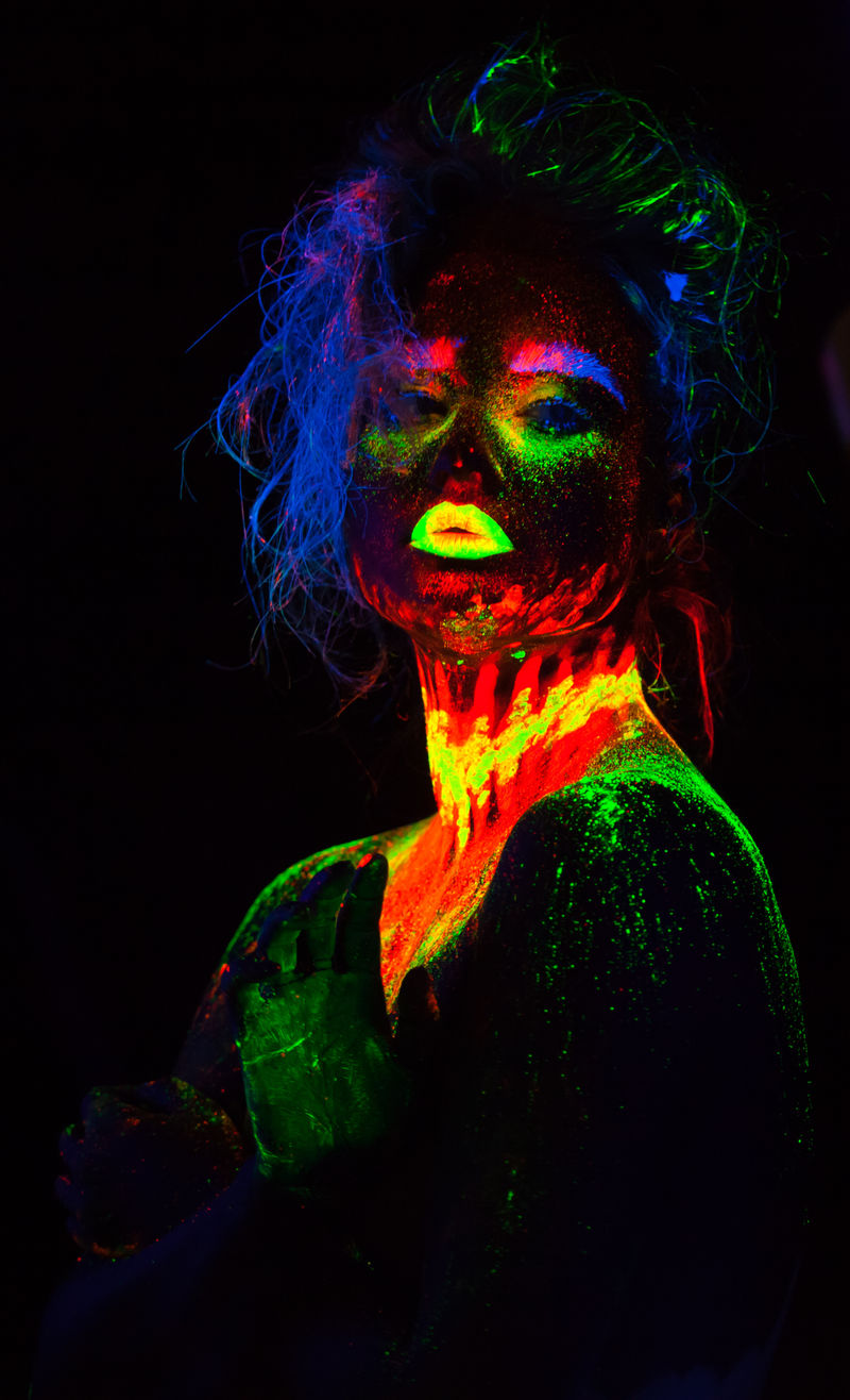 这是一幅荧光彩妆的美丽模特肖像,彩妆的女性在紫外光下摆姿势的艺术