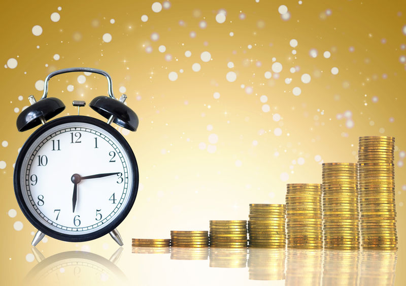 一堆堆金币与抽象照片上的老式时钟步调一致。