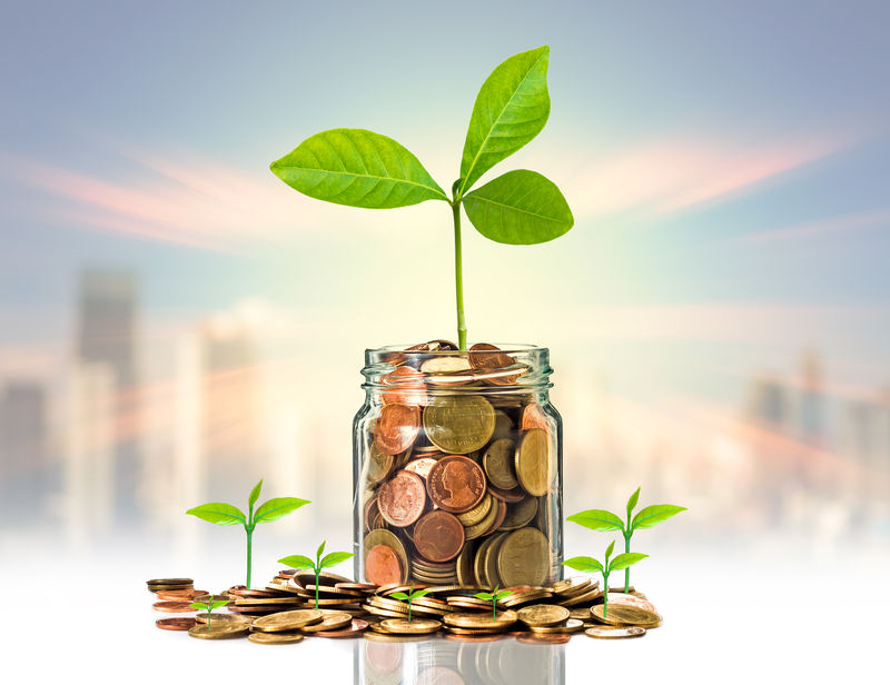 照片模糊的城市风景B上透明瓶子里的金币和种子