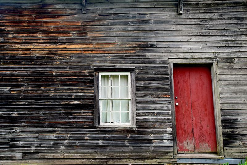 一扇旧的红门是一座朴素的木屋的入口