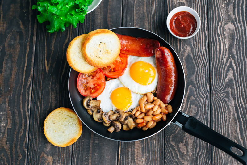 早餐番茄、香肠、豆类、蘑菇、鸡蛋、吐司和香草俯视图